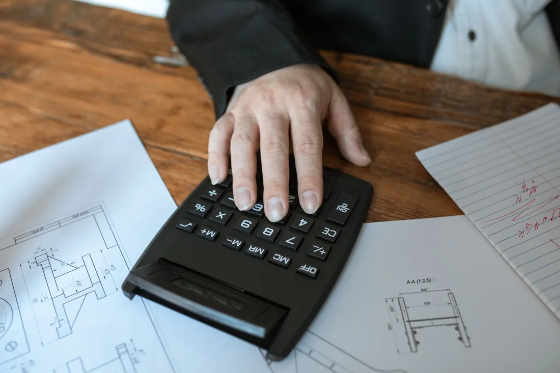 A calculator and small house model on a desk, the math behind how cash home buyers calculate their offer in Iowa