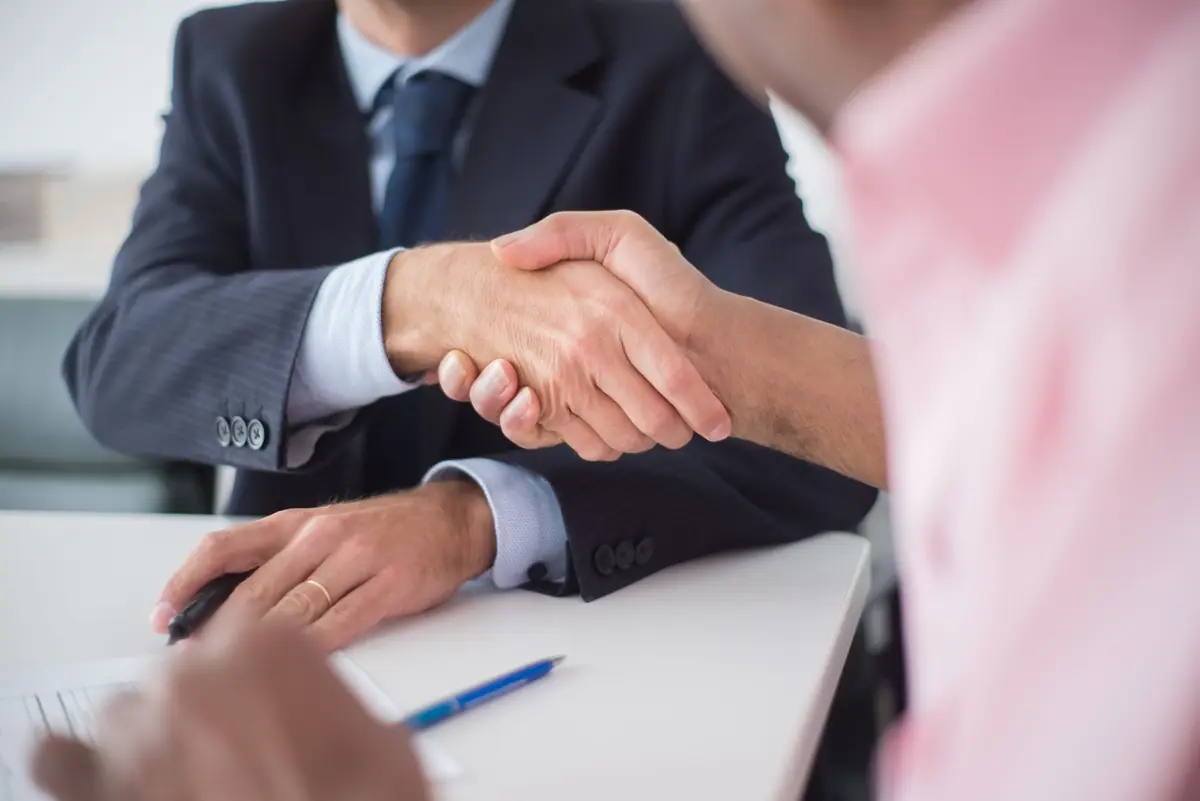 Two people shaking hands over a table after agreeing on a fair cash offer for an Iowa home
