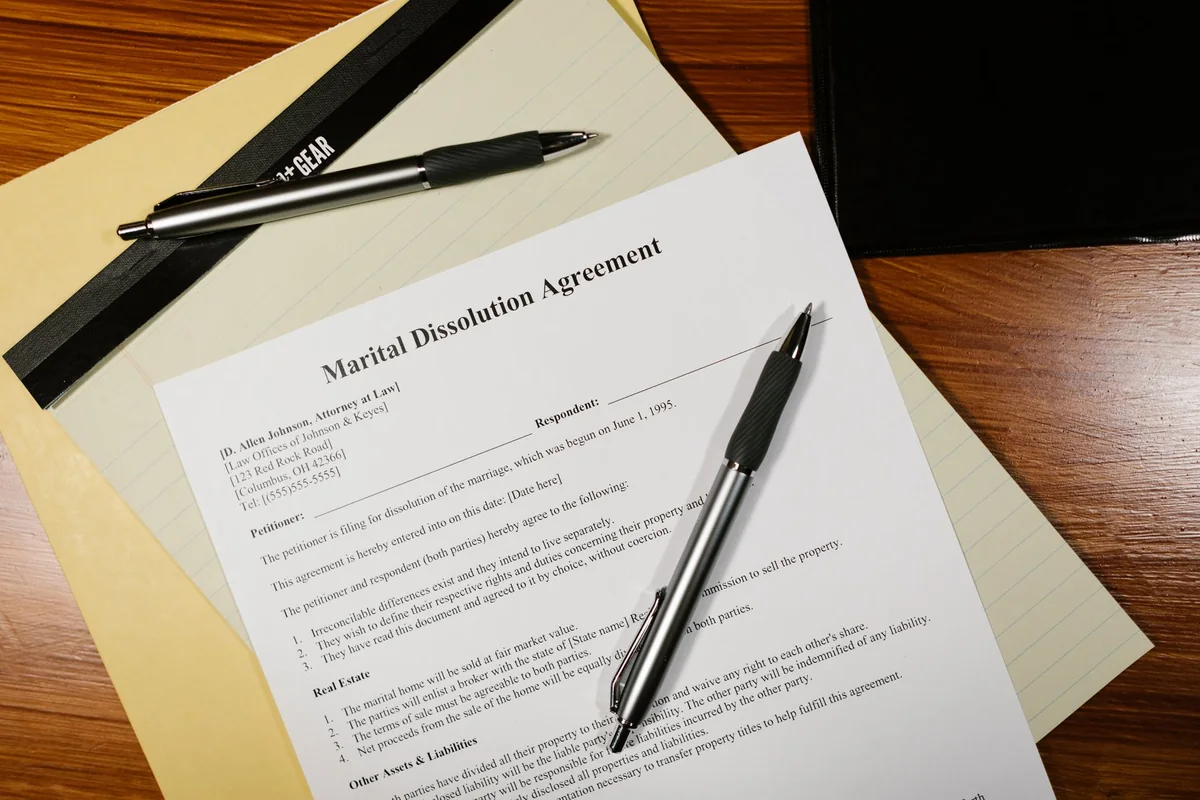 A dissolution of marriage agreement being signed alongside a mortgage refinance