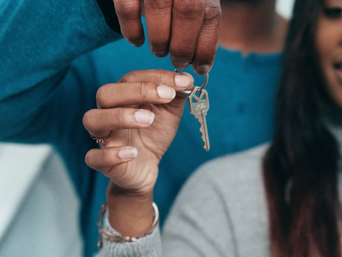 Two people passing a set of house keys, deciding who keeps the house in a divorce