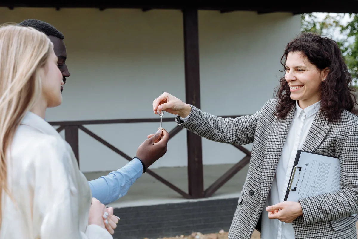 An agent handing house keys to new owners at the closing table