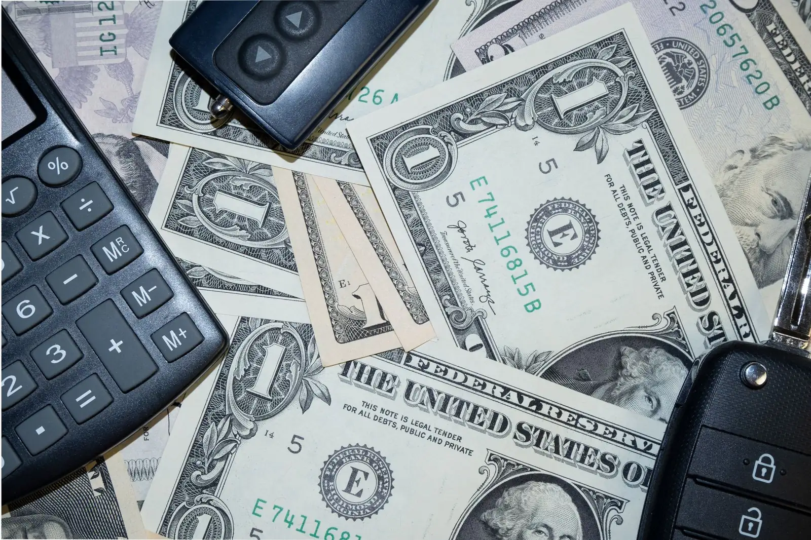 A calculator, money, and keys showing the cost of selling a house in Iowa