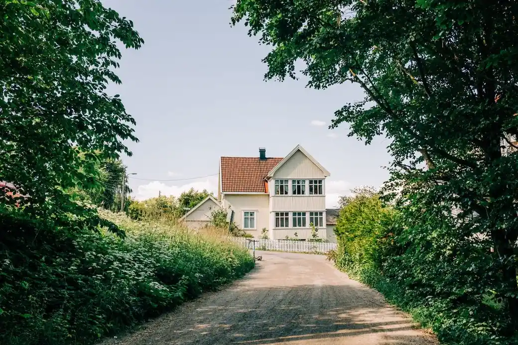 A rural white farmhouse on a wooded acreage, the kind of property in play when selling an acreage in Iowa