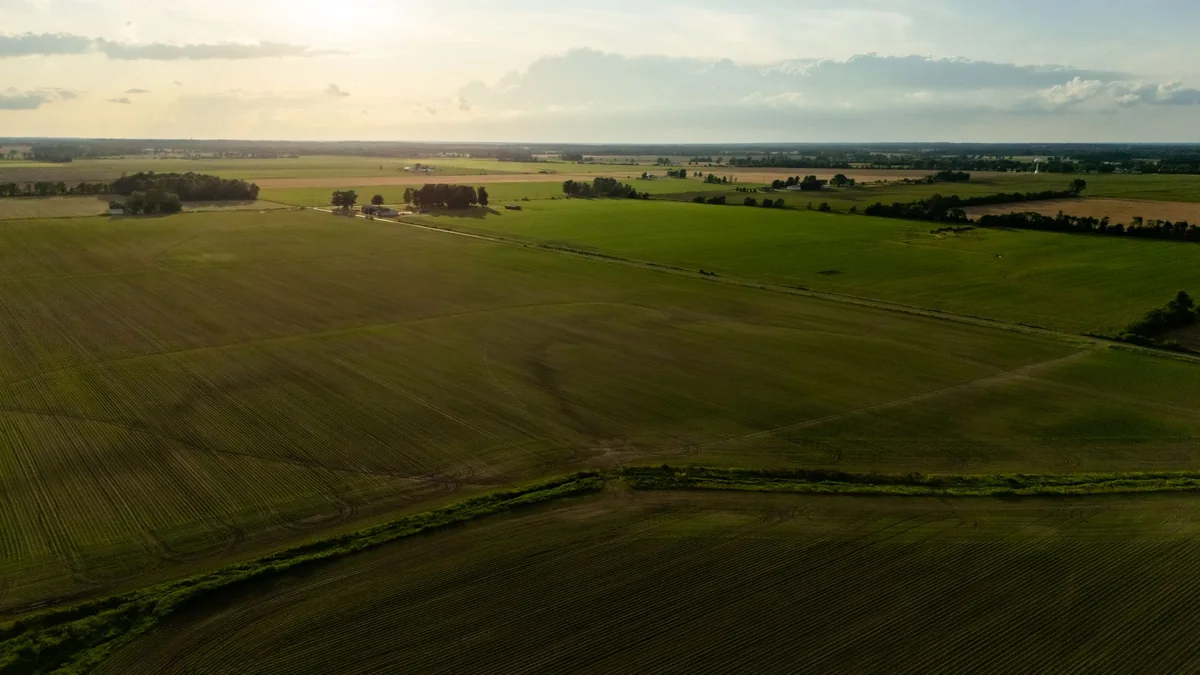 Aerial view of open Iowa farmland and acreage fields, the land half of selling an acreage in Iowa
