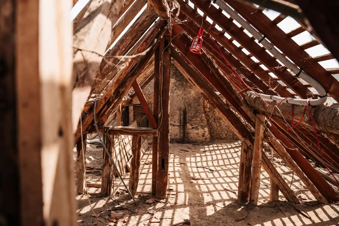 A dusty attic with exposed roof rafters, the kind of space wildlife takes over when you are selling a house with an animal infestation in Iowa