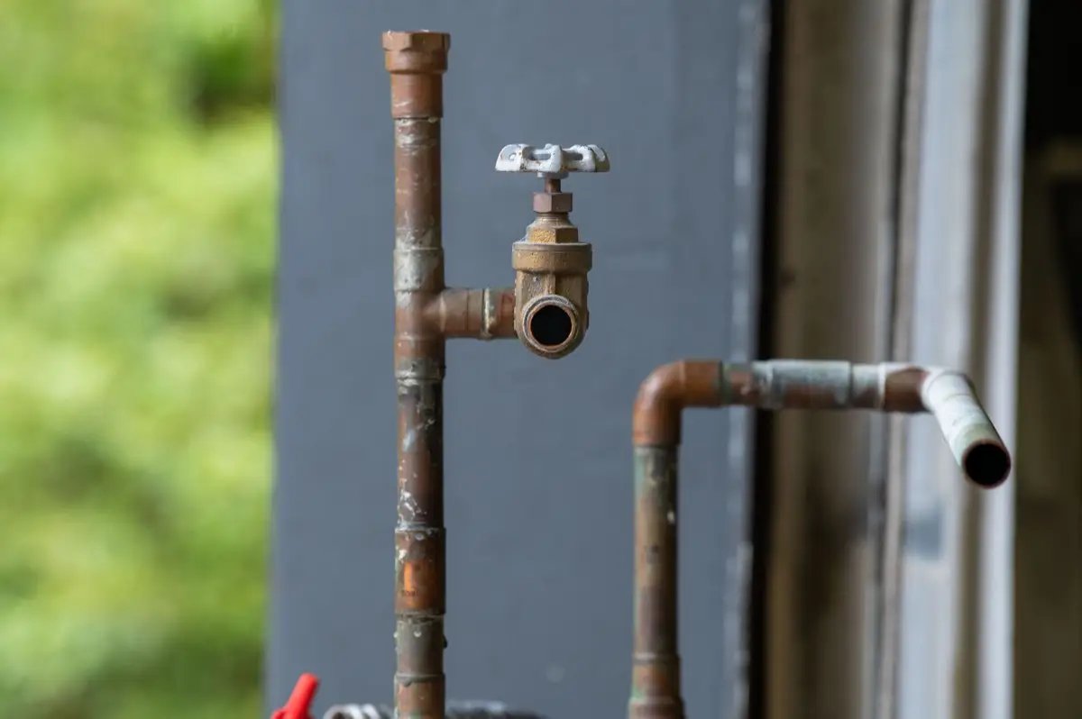 A close-up of a corroded, rusted pipe, the kind of aging sewer line that cracks and clogs under an Iowa house