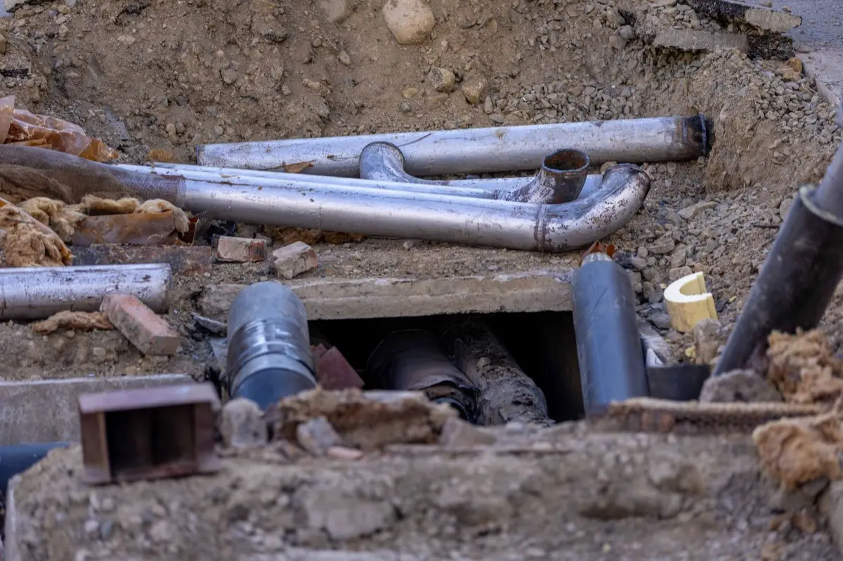 An open trench at a construction site exposing underground pipework, the kind of dig a collapsed sewer lateral can require