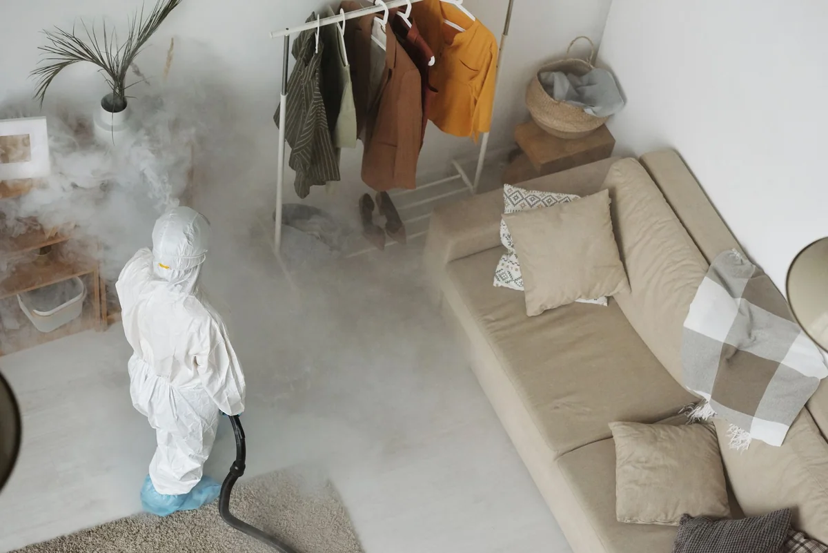 A pest control technician in protective gear spraying a room, the kind of professional treatment behind selling a house with a bug infestation in Iowa
