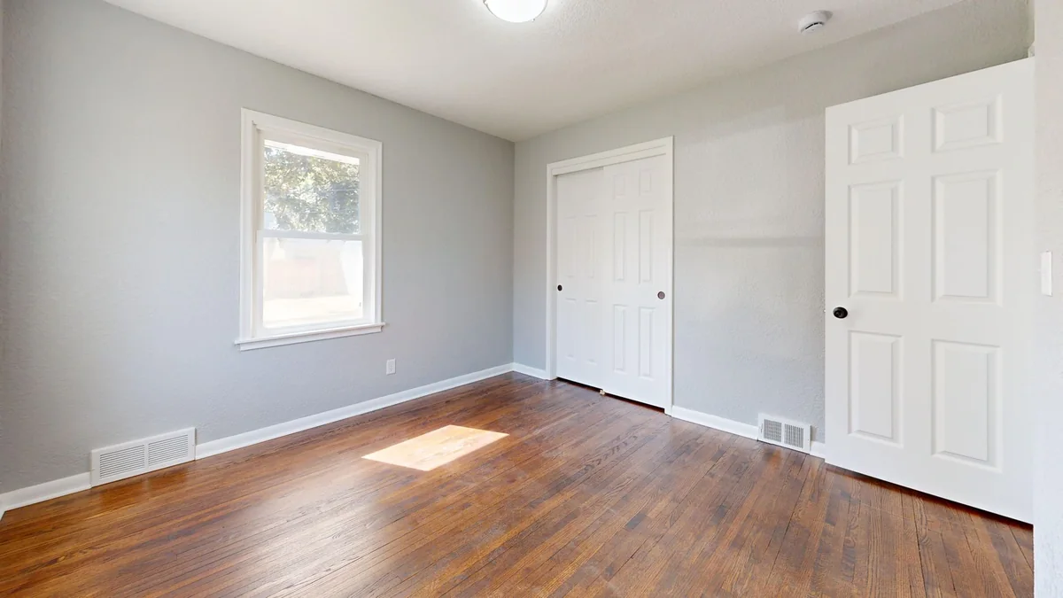 A bright, empty room with clean hardwood floors and baseboards, the opposite of what buyers fear when selling a house with a bug infestation in Iowa