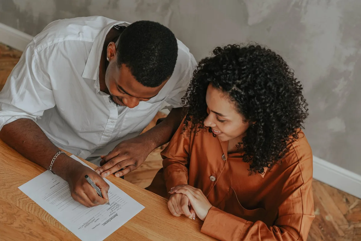 A person signing home closing documents to sell a house with back taxes