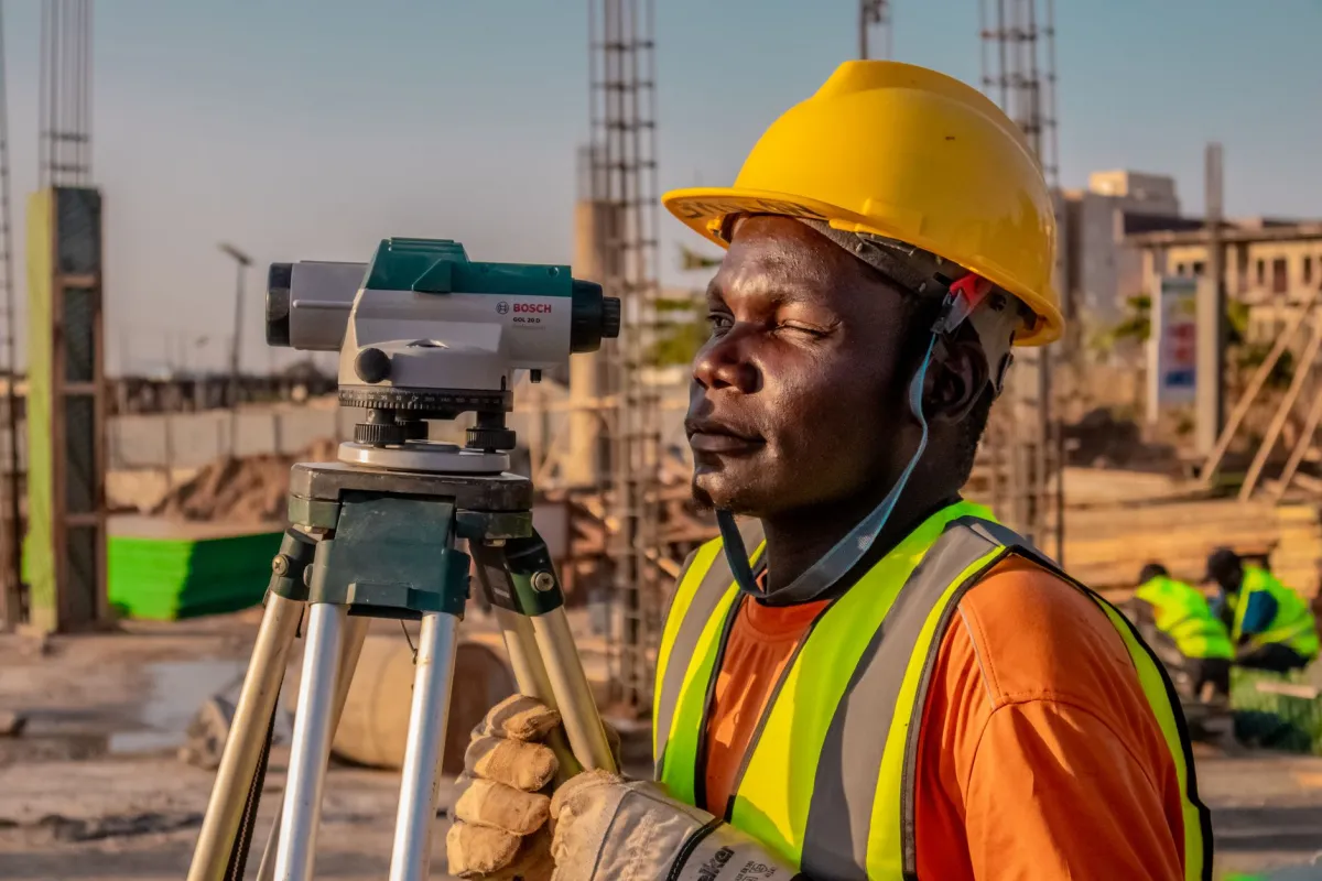 A land surveyor using tripod equipment outdoors to map a boundary and resolve an easement dispute