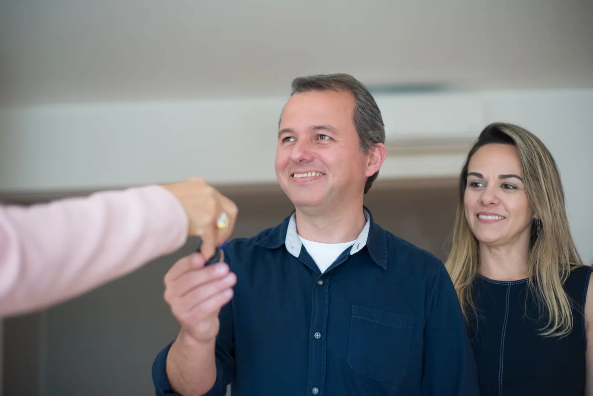 A couple receiving house keys from a cash buyer who purchased as-is after a failed inspection