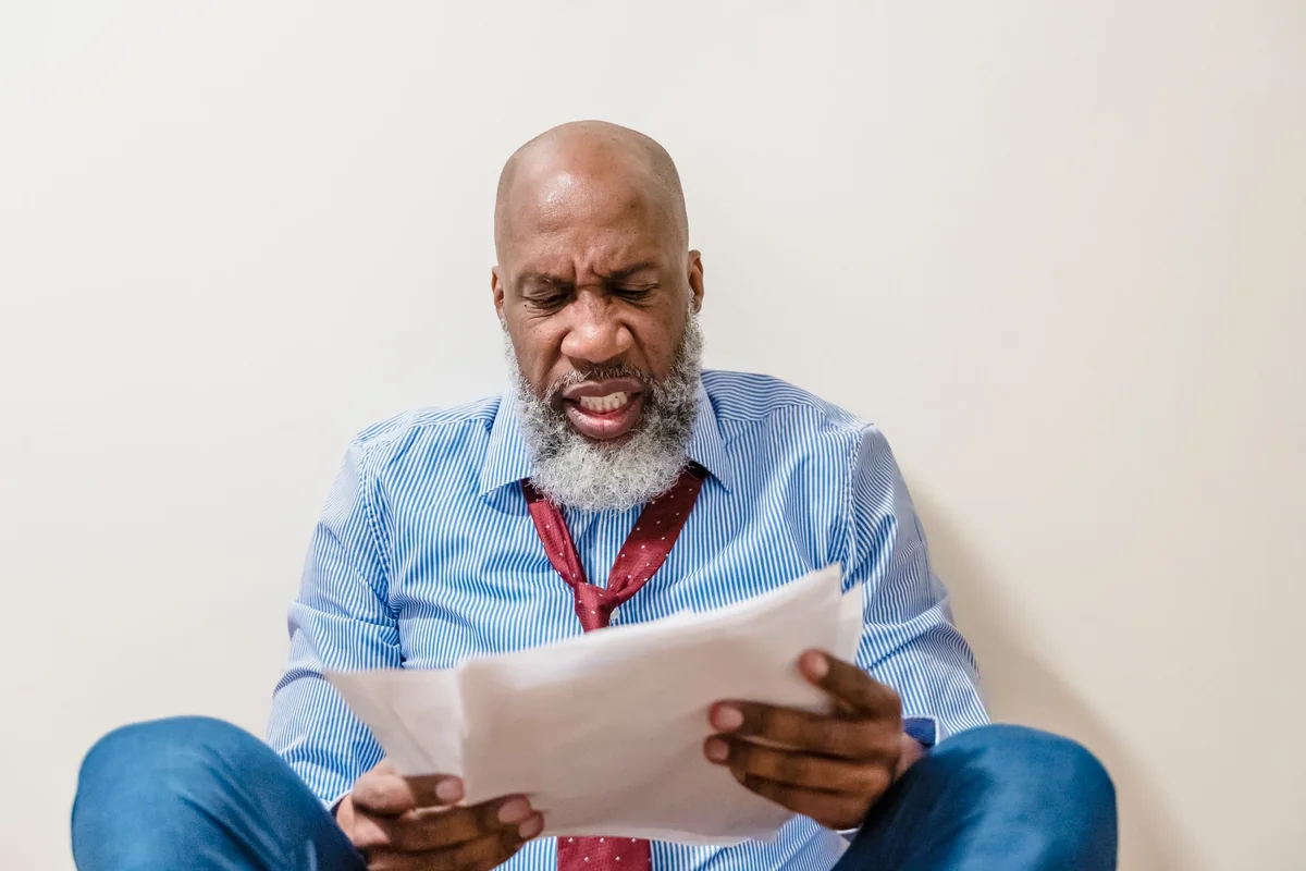 An Iowa homeowner reading paperwork, weighing options after a failed home inspection