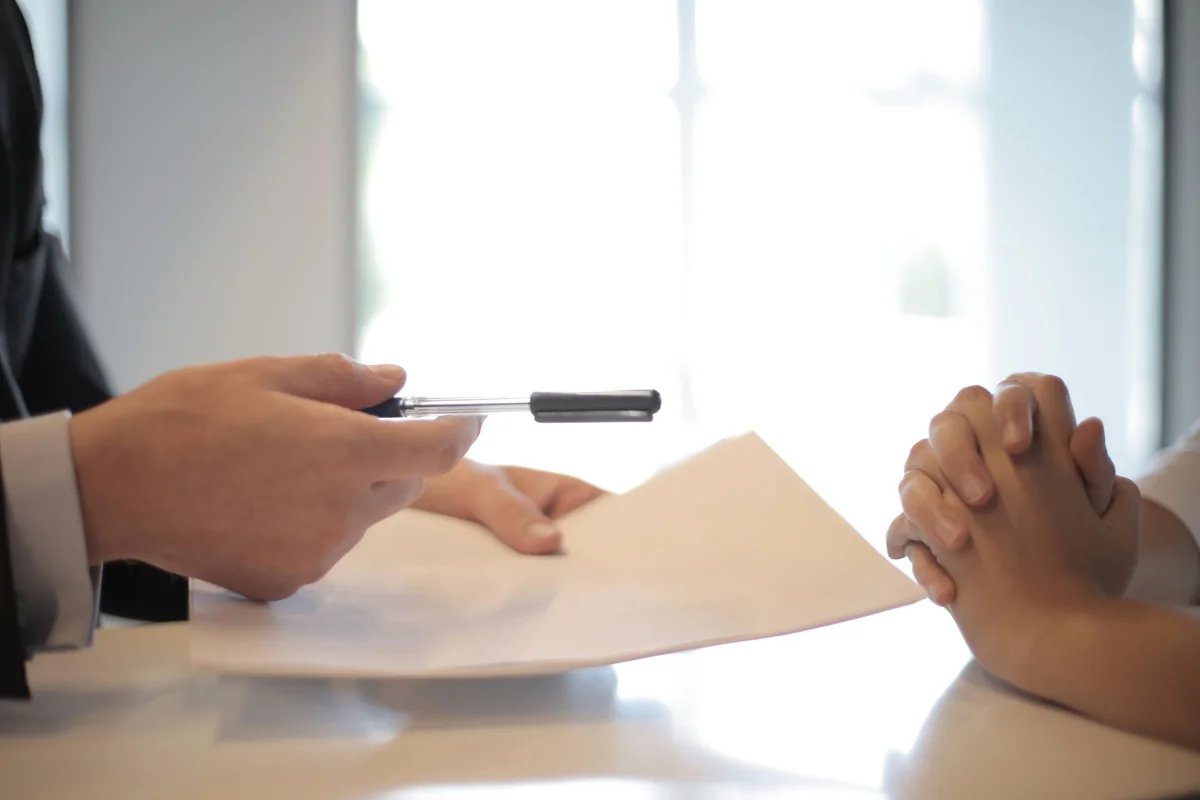 A buyer signing insurance paperwork, where lender-required flood insurance affects a flood-zone home sale