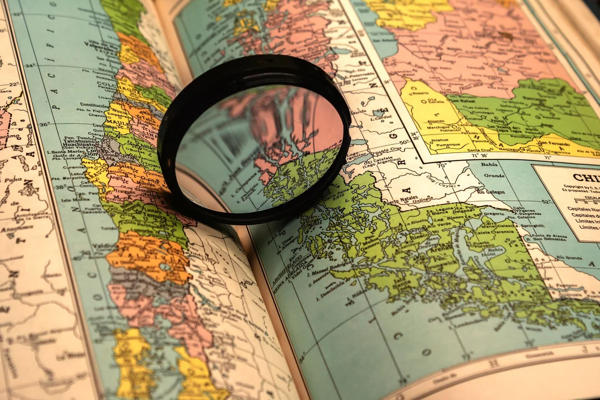 A magnifying glass over a map, used to check whether a house is in a FEMA flood zone