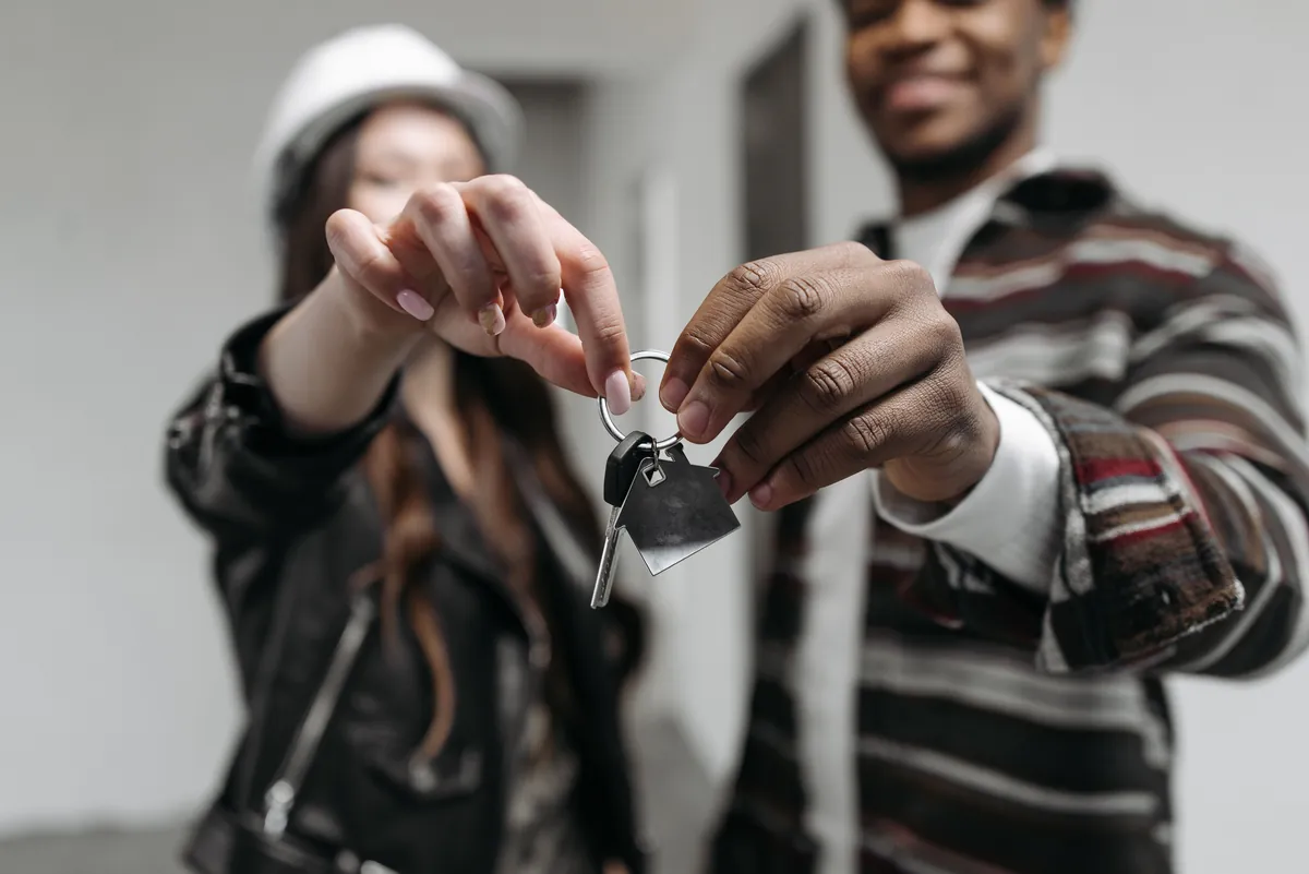 A couple holding a house key after selling their home for a job relocation