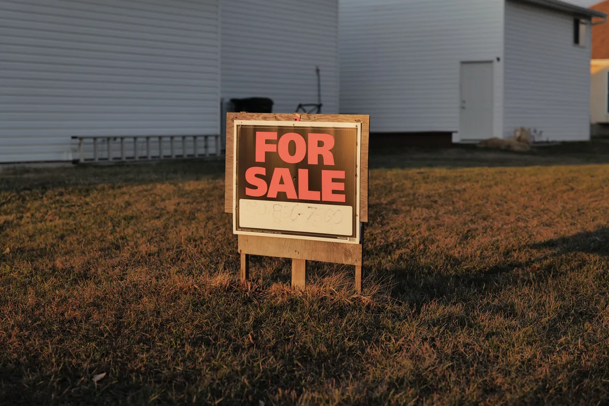 A for-sale sign in a suburban yard representing a fast cash sale for a relocation