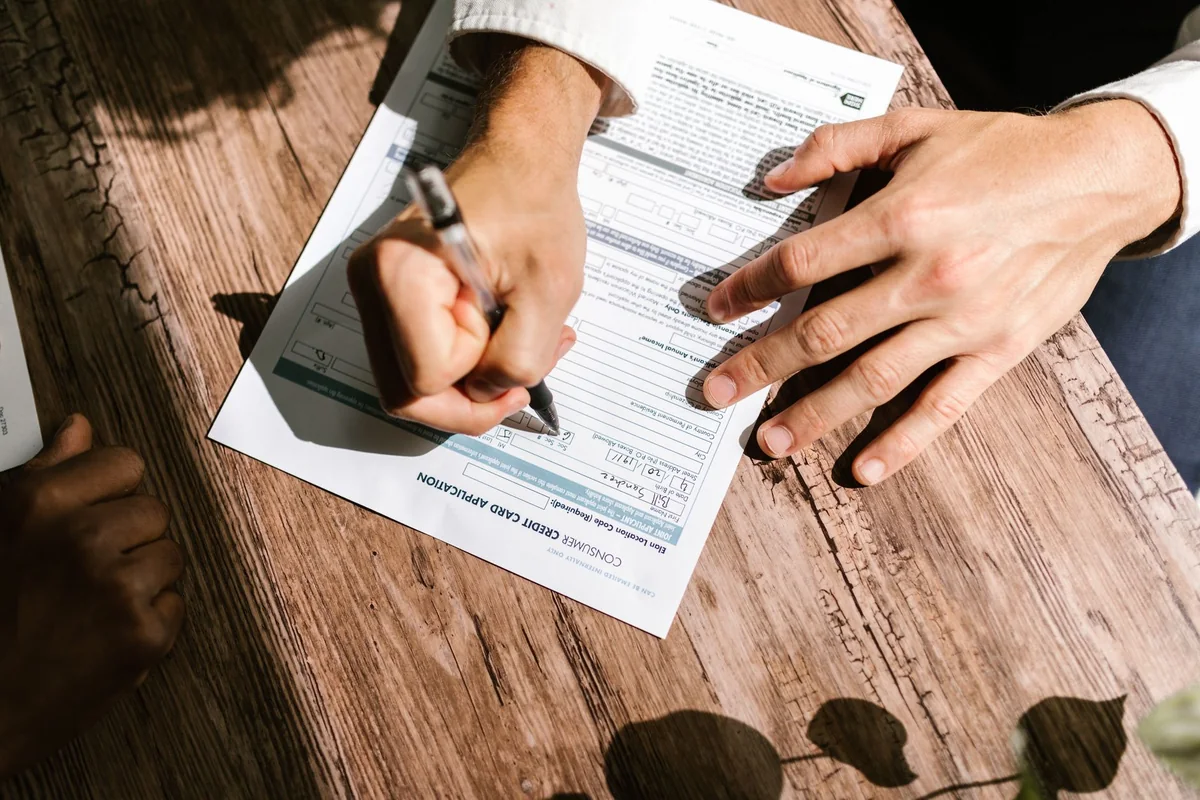 A person signing bank loan paperwork for a short sale on an underwater house in Iowa