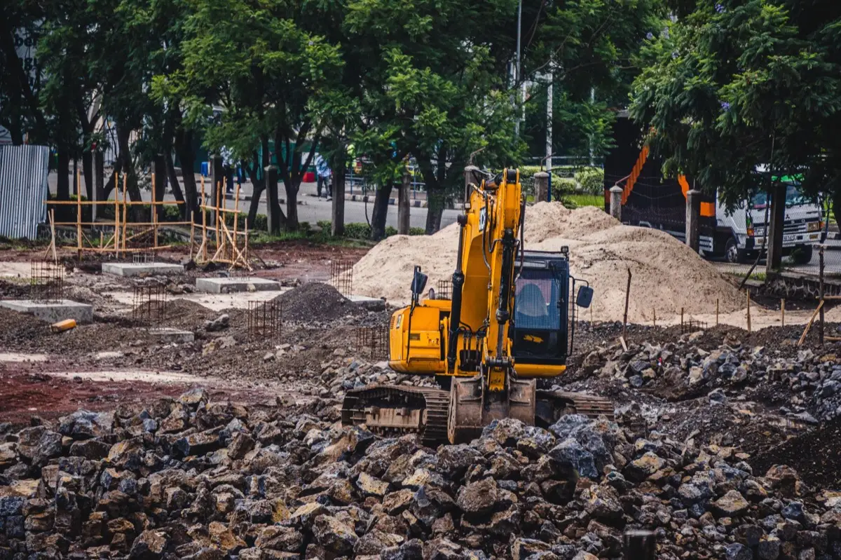 An excavator digging soil, the kind of equipment used to remove or professionally close out a buried oil tank