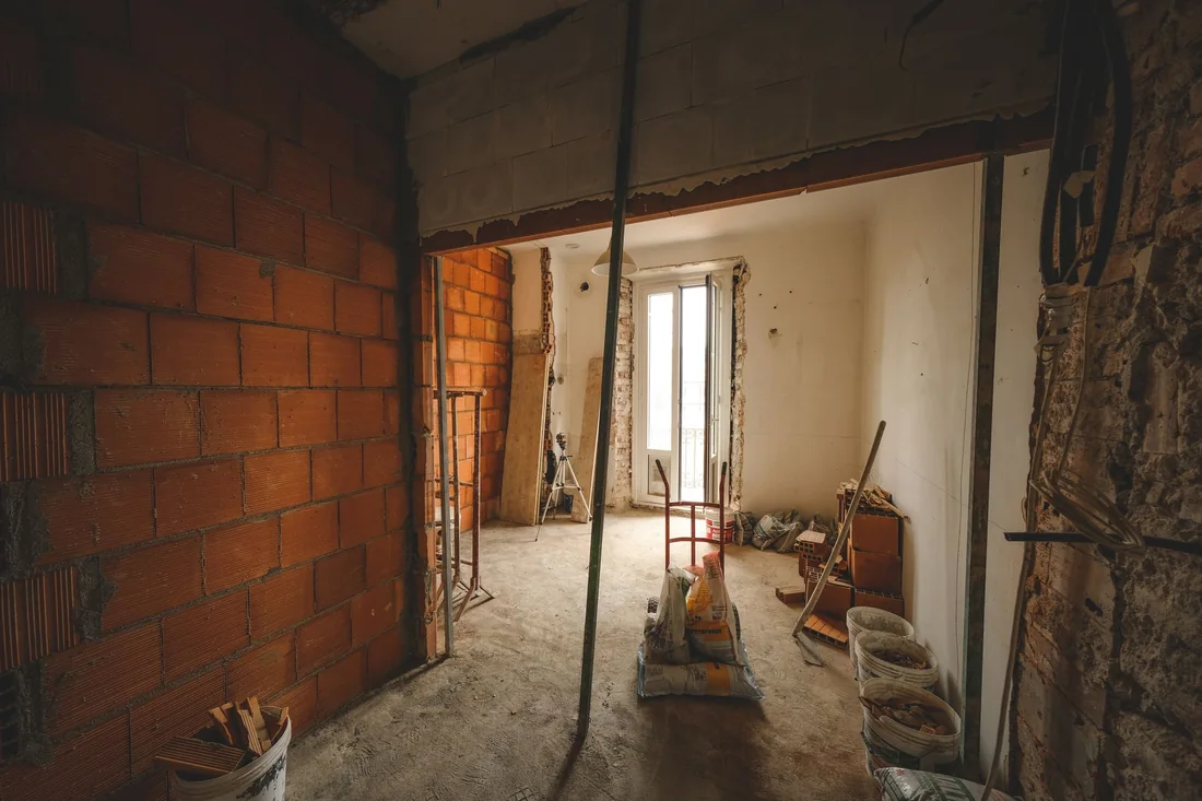 A room mid-remodel with exposed studs and bare subfloor, an unfinished renovation to deal with before selling an Iowa house