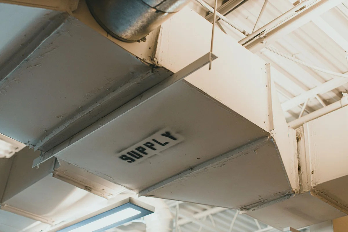 Old ductwork and pipes in a basement where asbestos was commonly used
