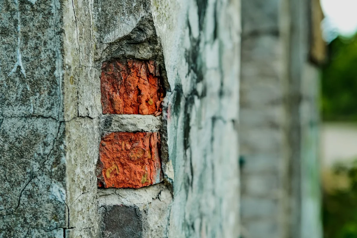 Close-up of a brick chimney with spalling, crumbling brick and eroded mortar joints, a common bad-chimney defect