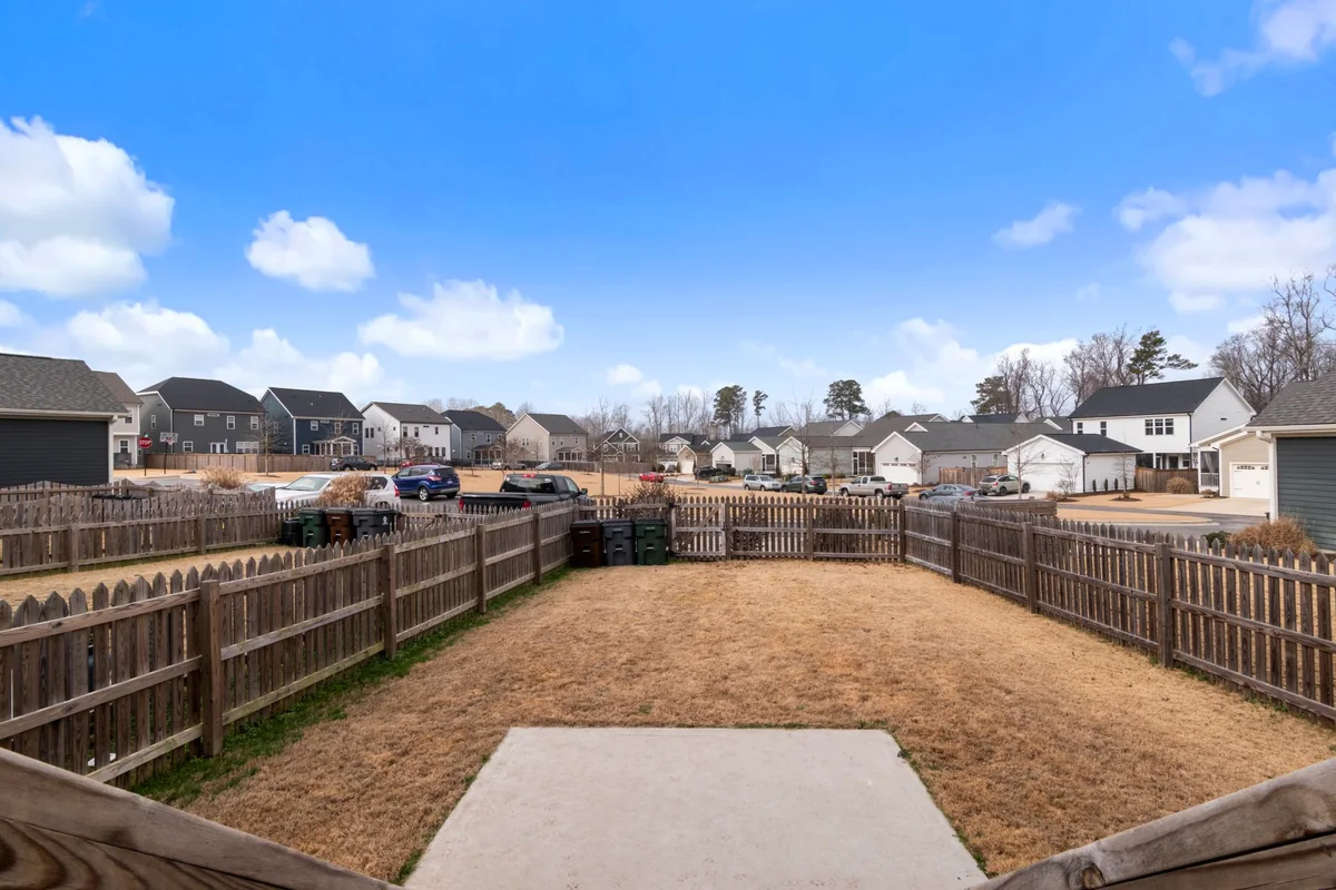 A fenced backyard with trash bins along the property line and neighboring houses behind, relevant to Iowa seller disclosure duties