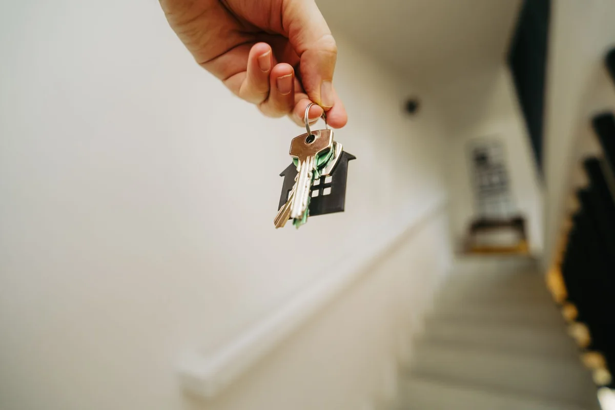 A hand holding house keys after selling a house with a bad roof for cash