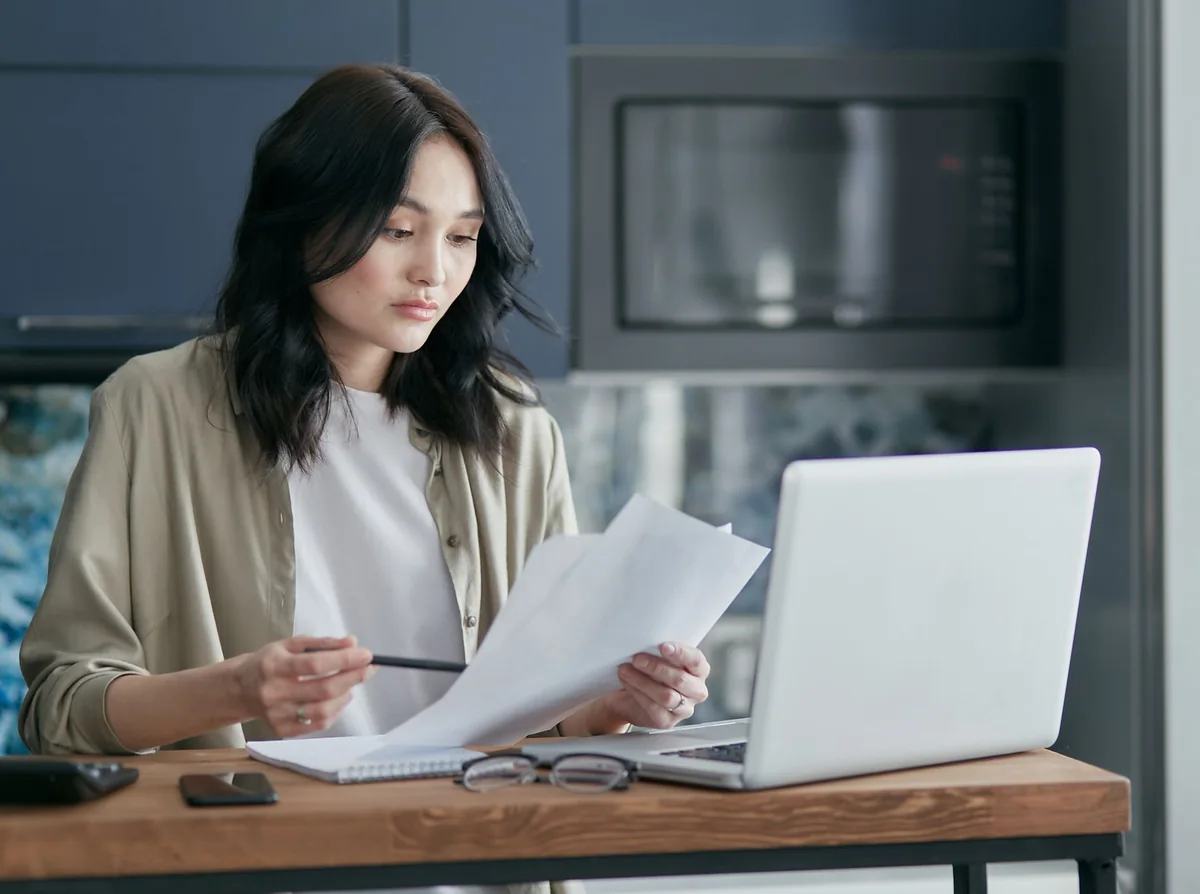 A homeowner reading paperwork at a table, weighing options for selling a house with a bad well