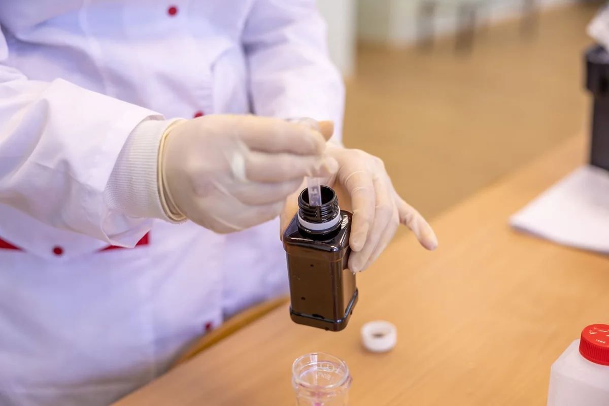 A lab technician drawing a water sample into a bottle to test an Iowa private well