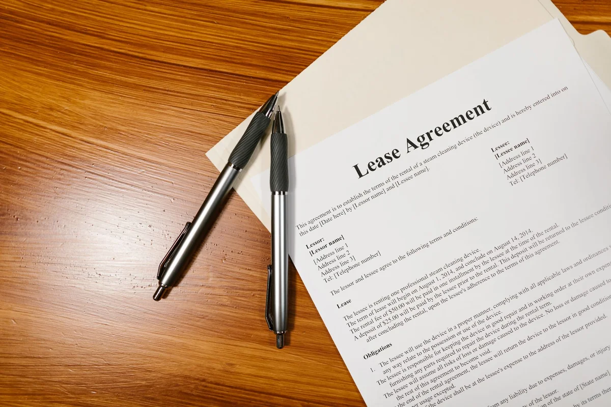 A person signing real estate documents with a pen, disclosing a solar lease when selling a house in Iowa