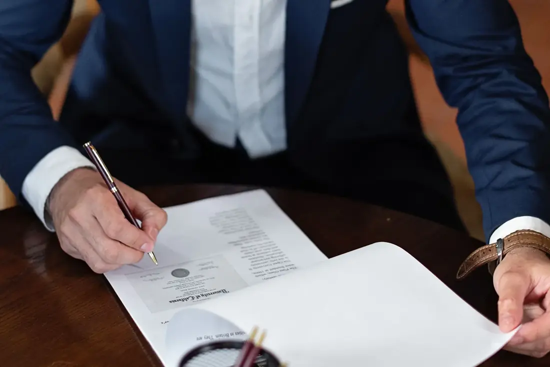A homeowner signing legal documents to sell a house with a lien on it