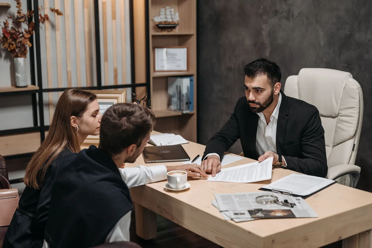 A worried couple reviewing paperwork with a loan officer, whose lender will not finance a house with a lis pendens