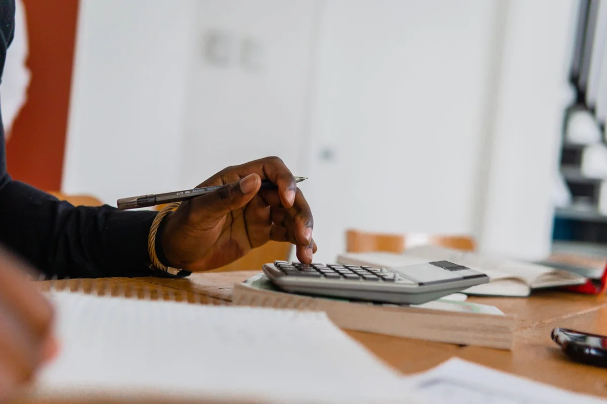A person with a calculator and pen reviewing a contractor invoice, the double-payment risk behind a mechanic's lien