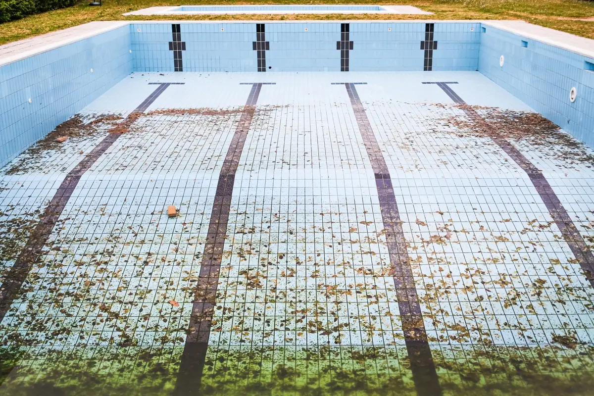 An empty, drained in-ground pool, one of the situations when deciding how to sell a house with an old pool as-is