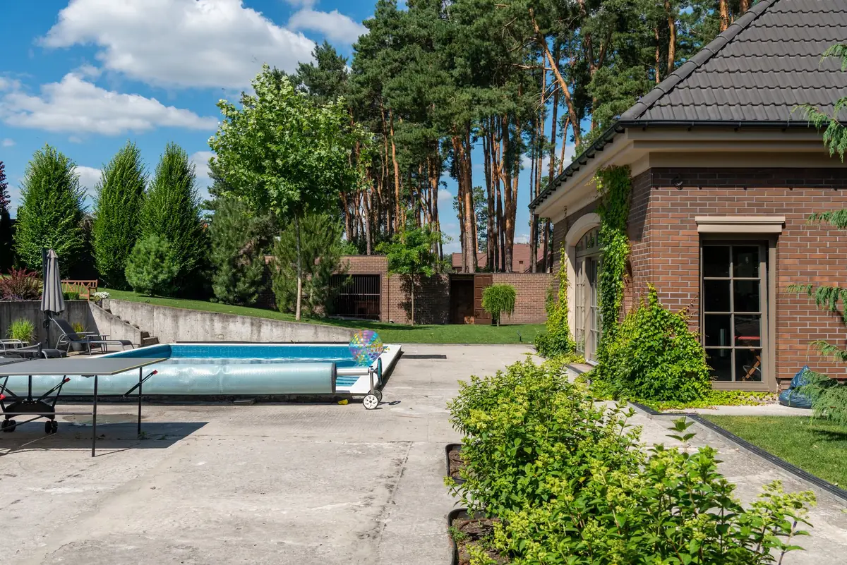 An in-ground swimming pool in a residential backyard next to a house, weighing whether a pool adds value when selling in Iowa