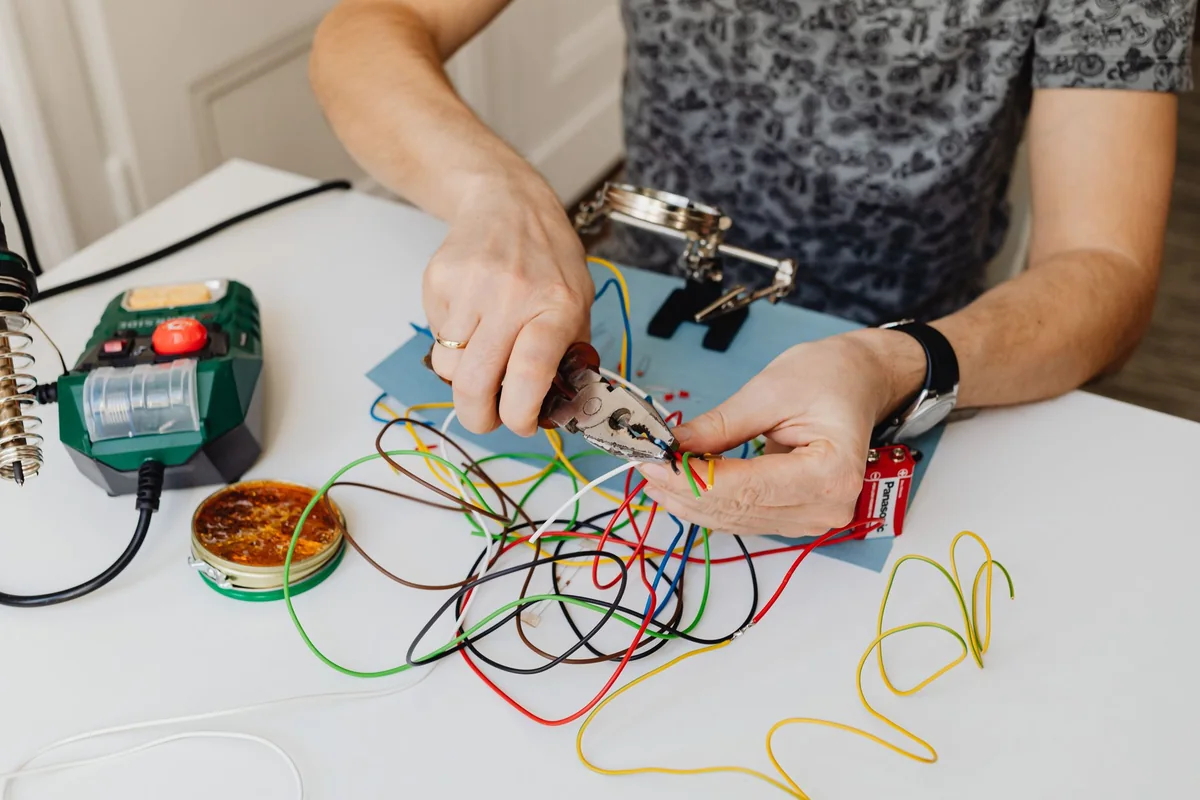A person working on colored electrical wires, one of three ways to handle old wiring before selling