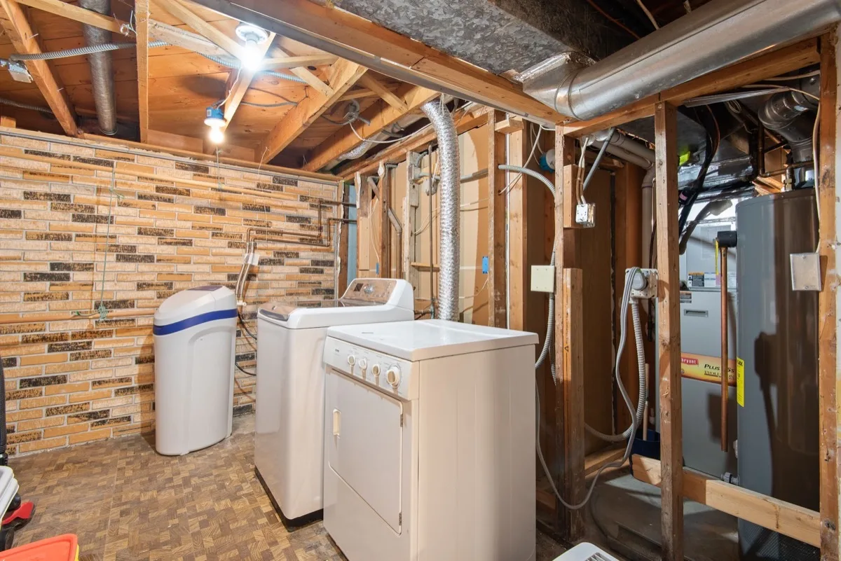 A basement with utilities and foundation walls, where a radon mitigation system is installed