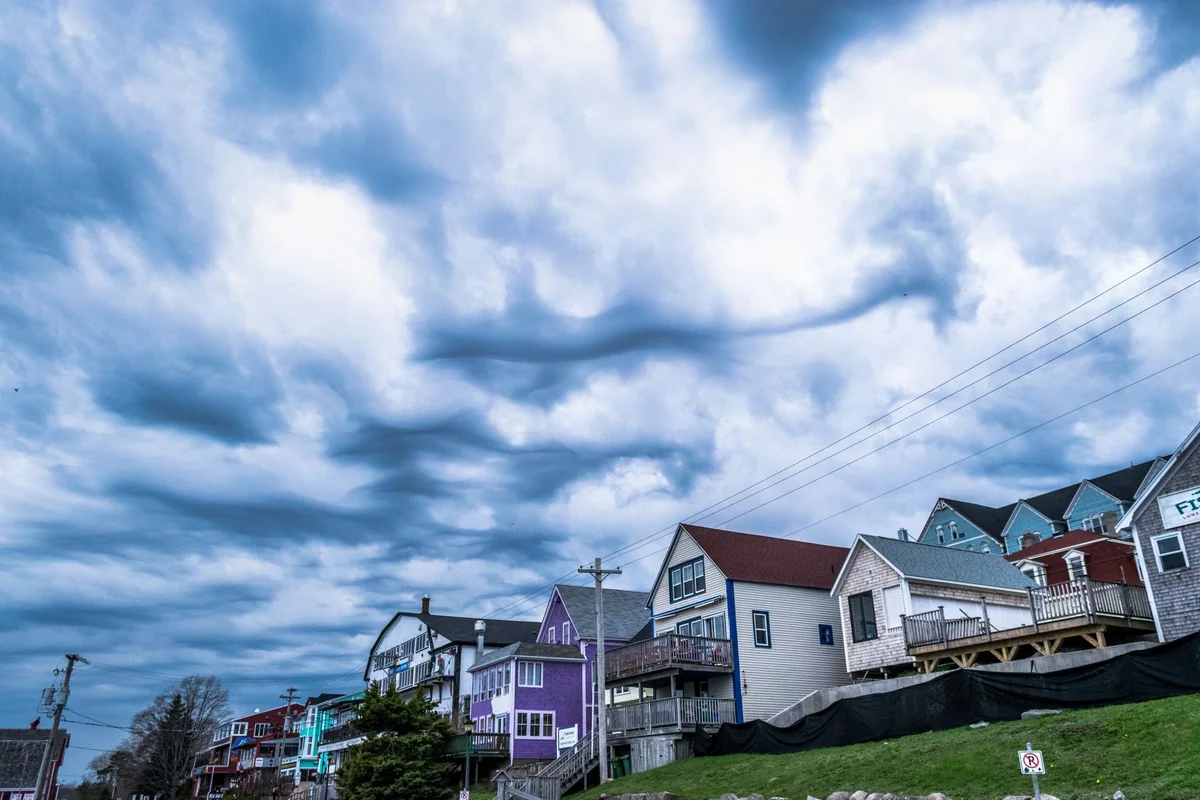 Storm clouds gathering over a house that a seller must disclose damage on in Iowa