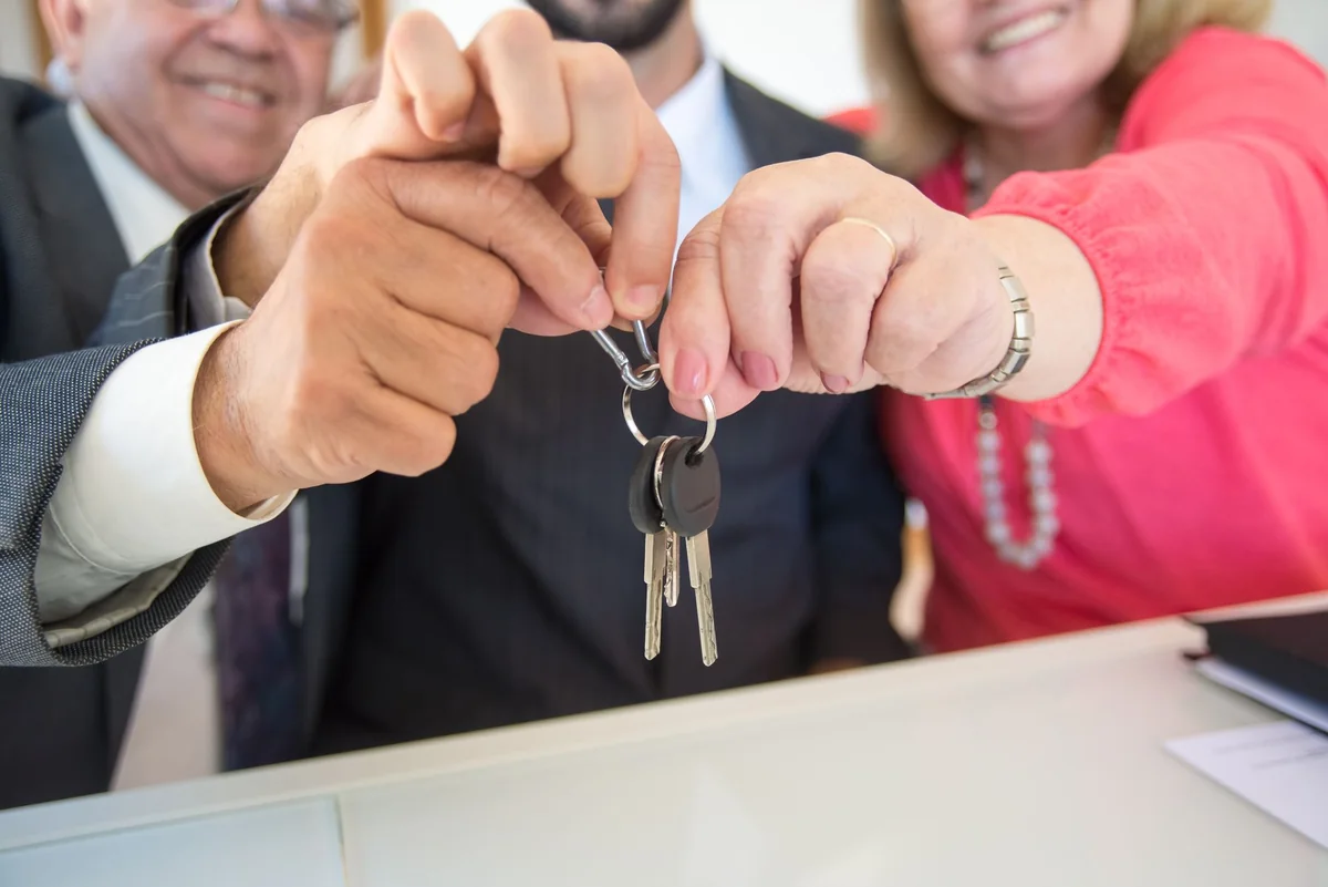 An investor shaking hands and taking the keys to a tenant-occupied Iowa rental