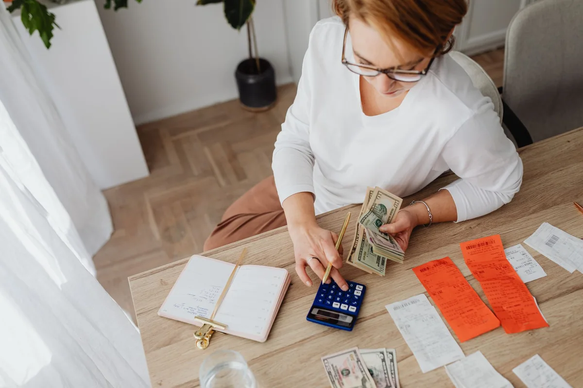 A calculator, cash, and house keys on a desk, showing how a cash offer on a termite-damaged house is figured