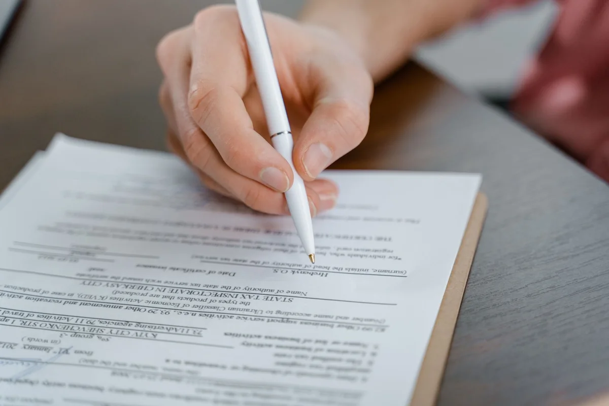 A hand signing a corrective deed to clear an Iowa title defect