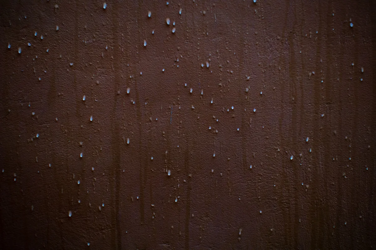 Beads of water seeping down a dark basement wall from hydrostatic pressure, a common cause of a chronically wet basement