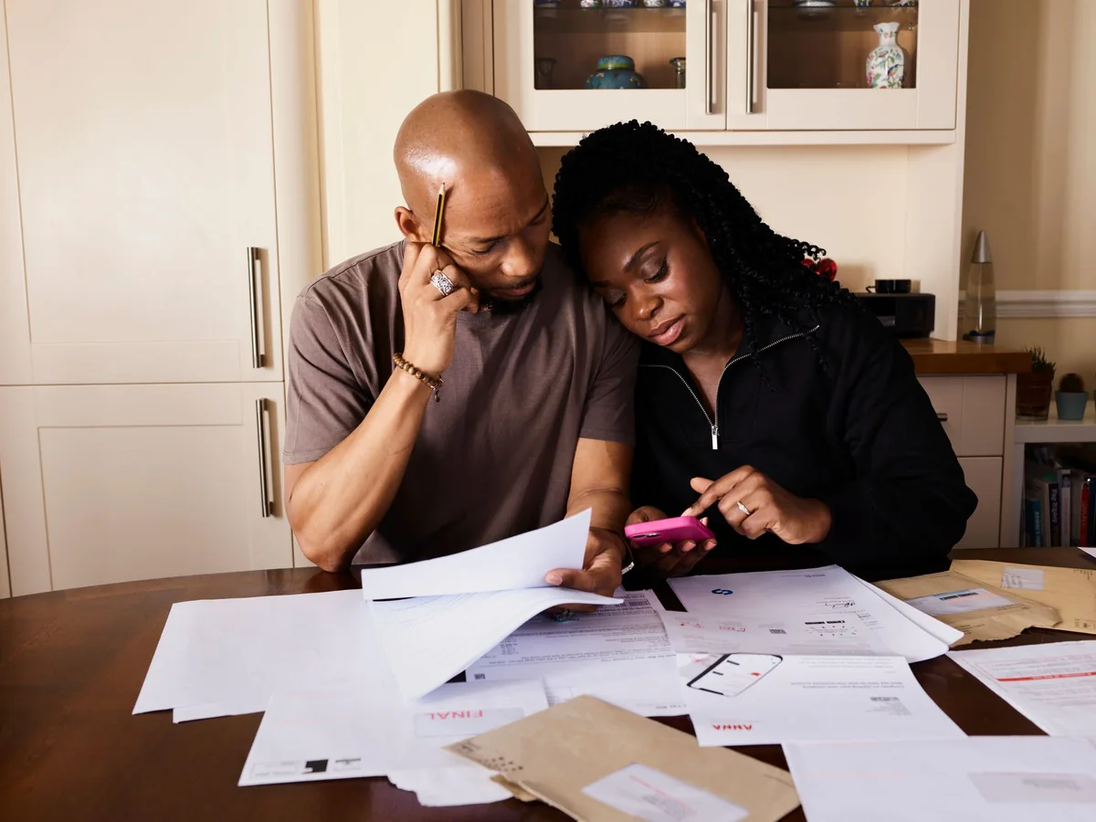 A couple at a kitchen table reviewing paperwork and weighing whether to fix a wet basement or sell the house as-is