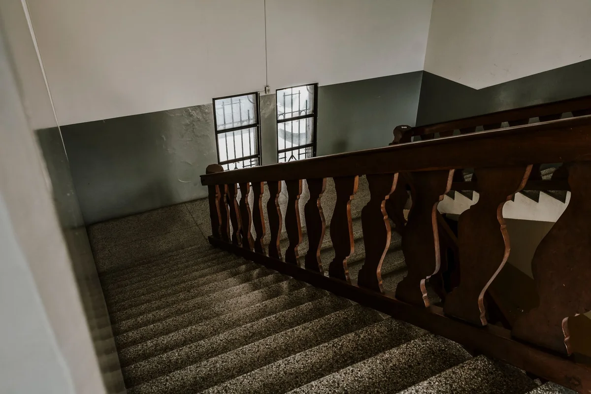 An interior wooden staircase in an older home, where a missing handrail is a common FHA safety flag