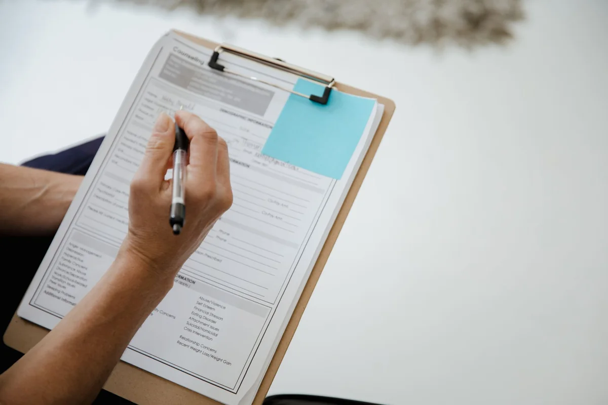 A person holding a clipboard and pen, noting deficiencies during an FHA appraisal walk-through