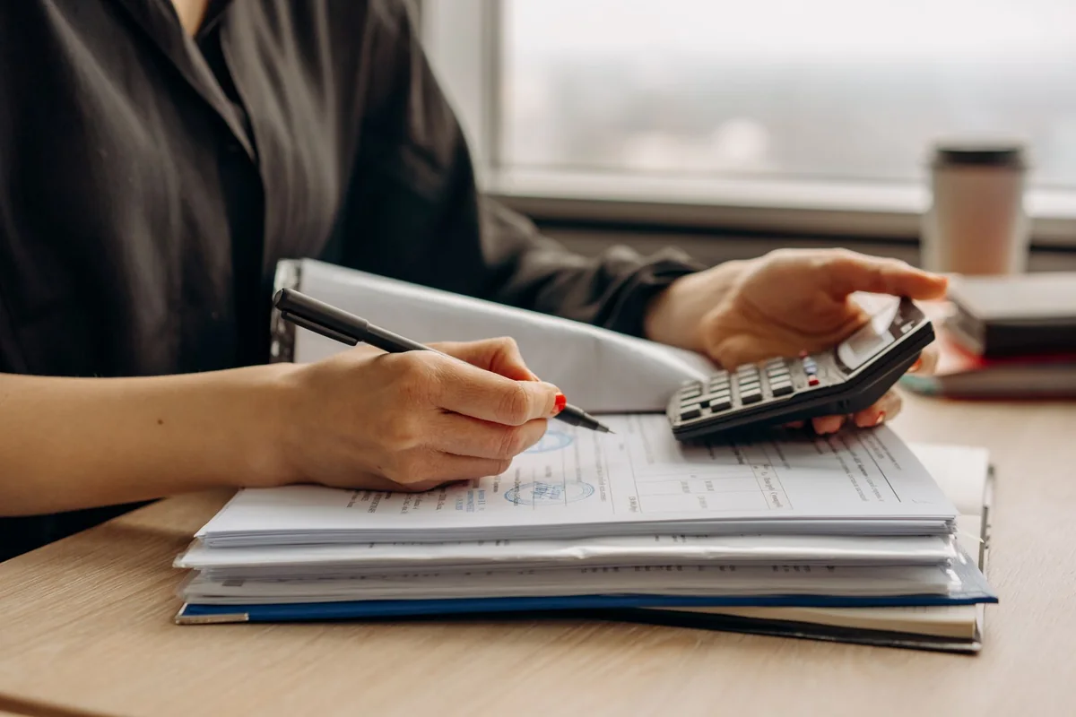 A person running numbers with a calculator and paperwork, weighing financing when selling a mobile home in Iowa