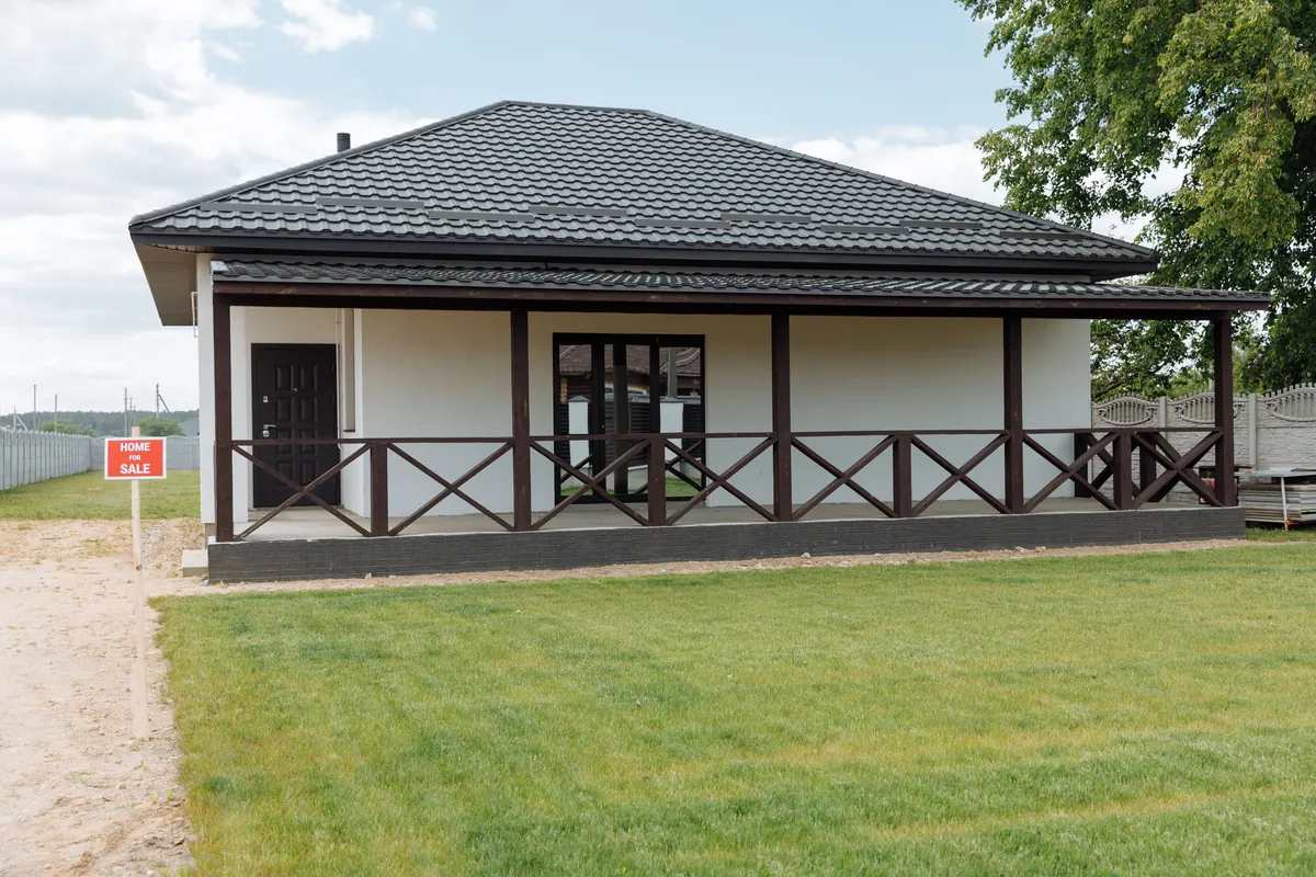 A vacant house exterior with a lawn, sitting empty and for sale