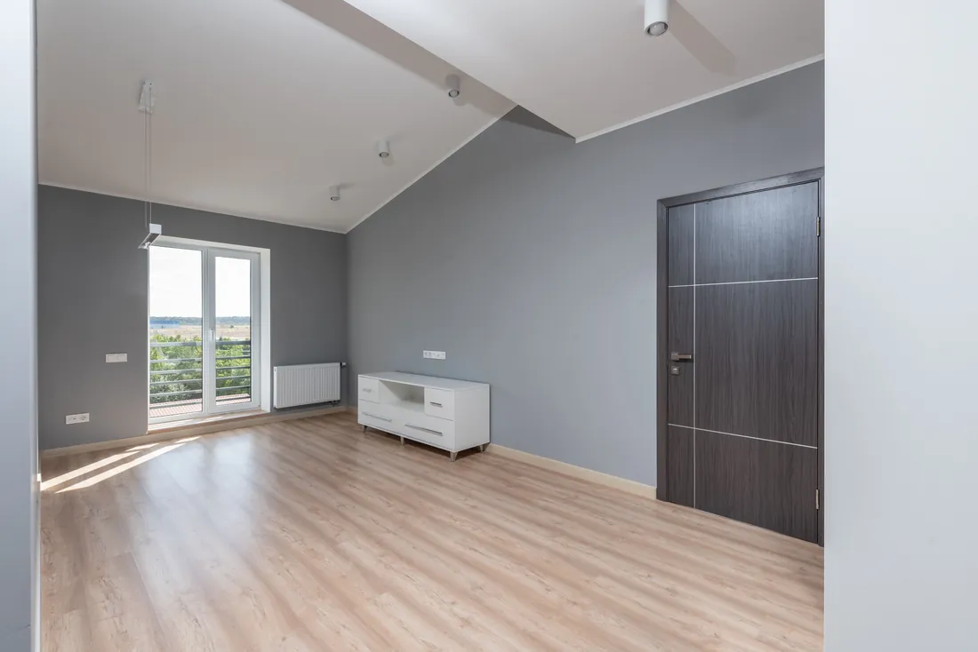 An empty room in a vacant house for sale in Iowa with hardwood floors and large windows
