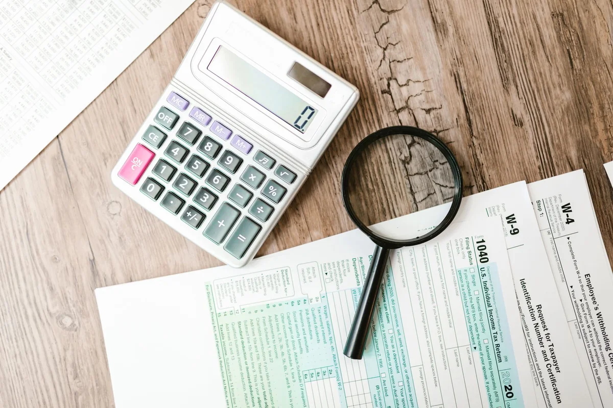 A magnifying glass and calculator over documents, a reminder to verify a cash home buyer before selling a house in Iowa